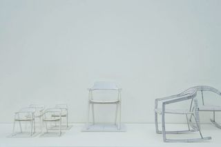 White chairs in different sizes on display in the white room of a gallery