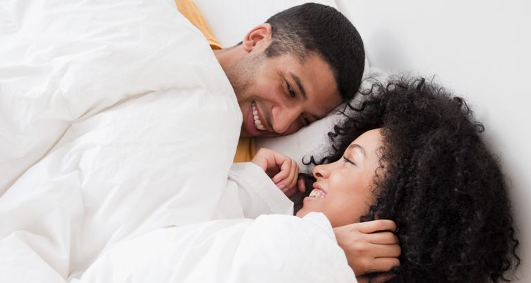 Young couple laying in bed and smiling
