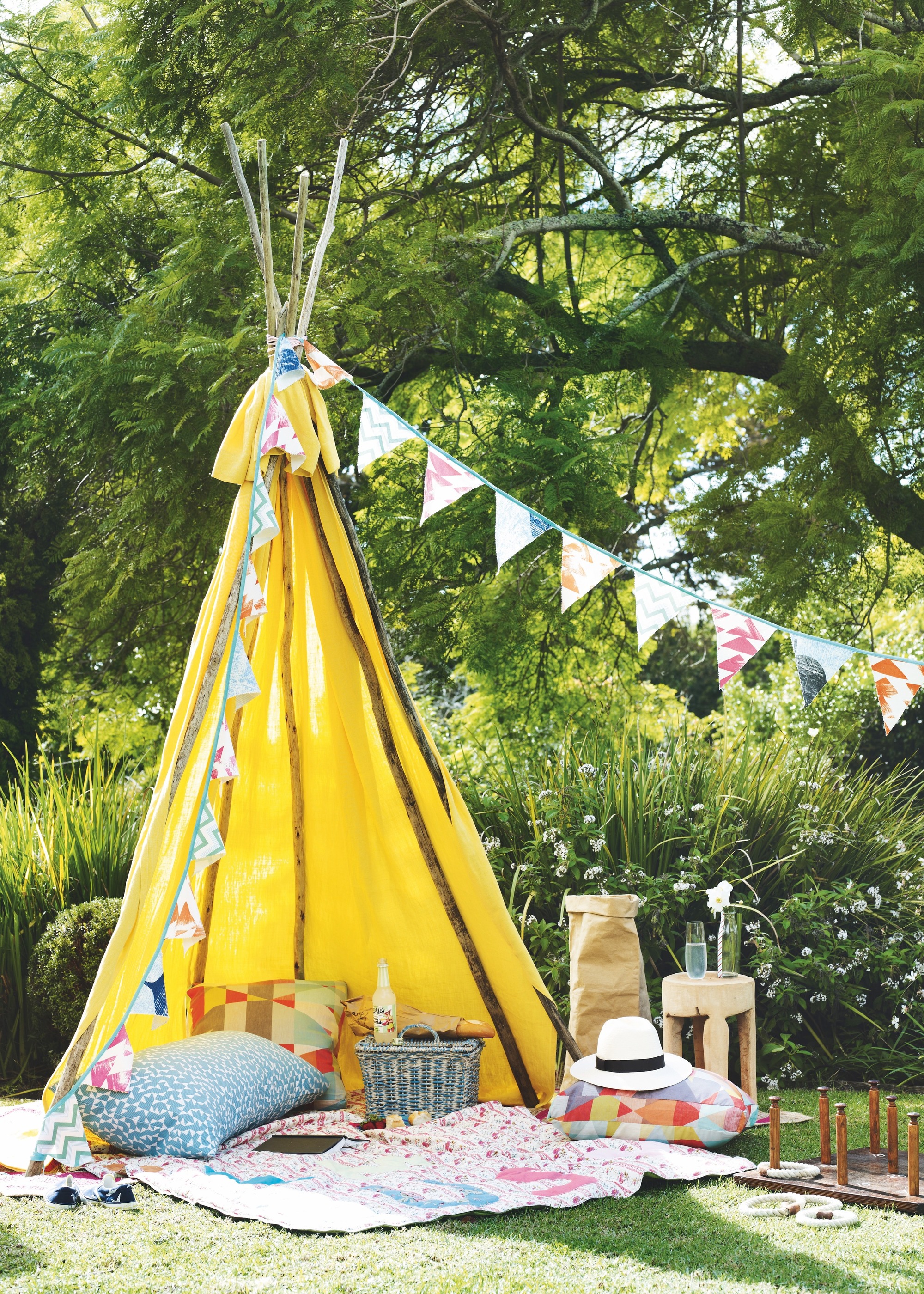 yellow tent on lawn with cushions and bunting
