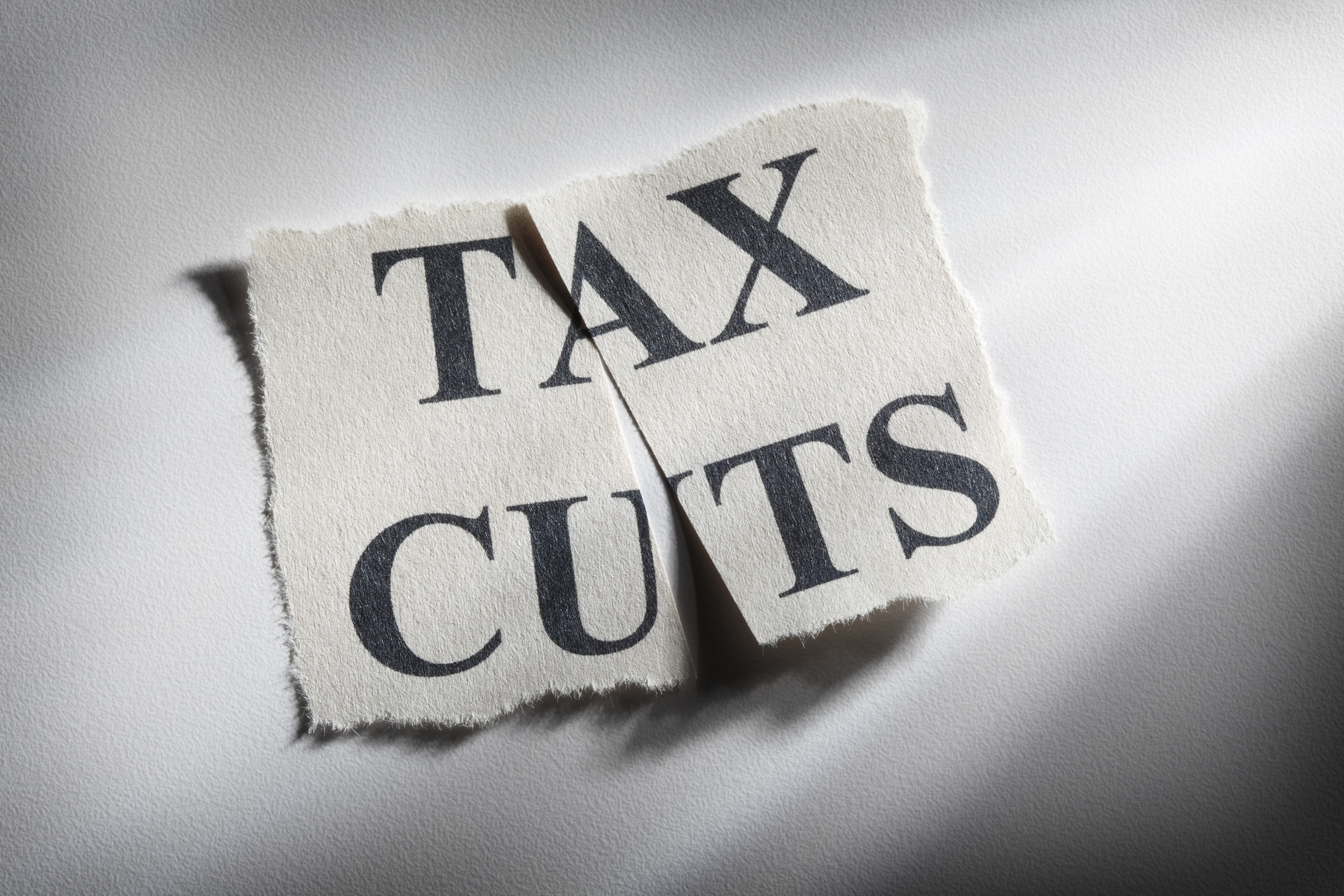 "tax cuts" printed on paper that is cut in half