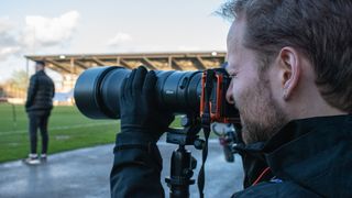 Man uses Nikon Z 6II and Nikon Z 180-600mm f/5.6-6.3 VR lens from soccer pitch sidelines