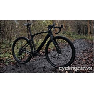 A black Pinarello Grevil stands on a muddy trail