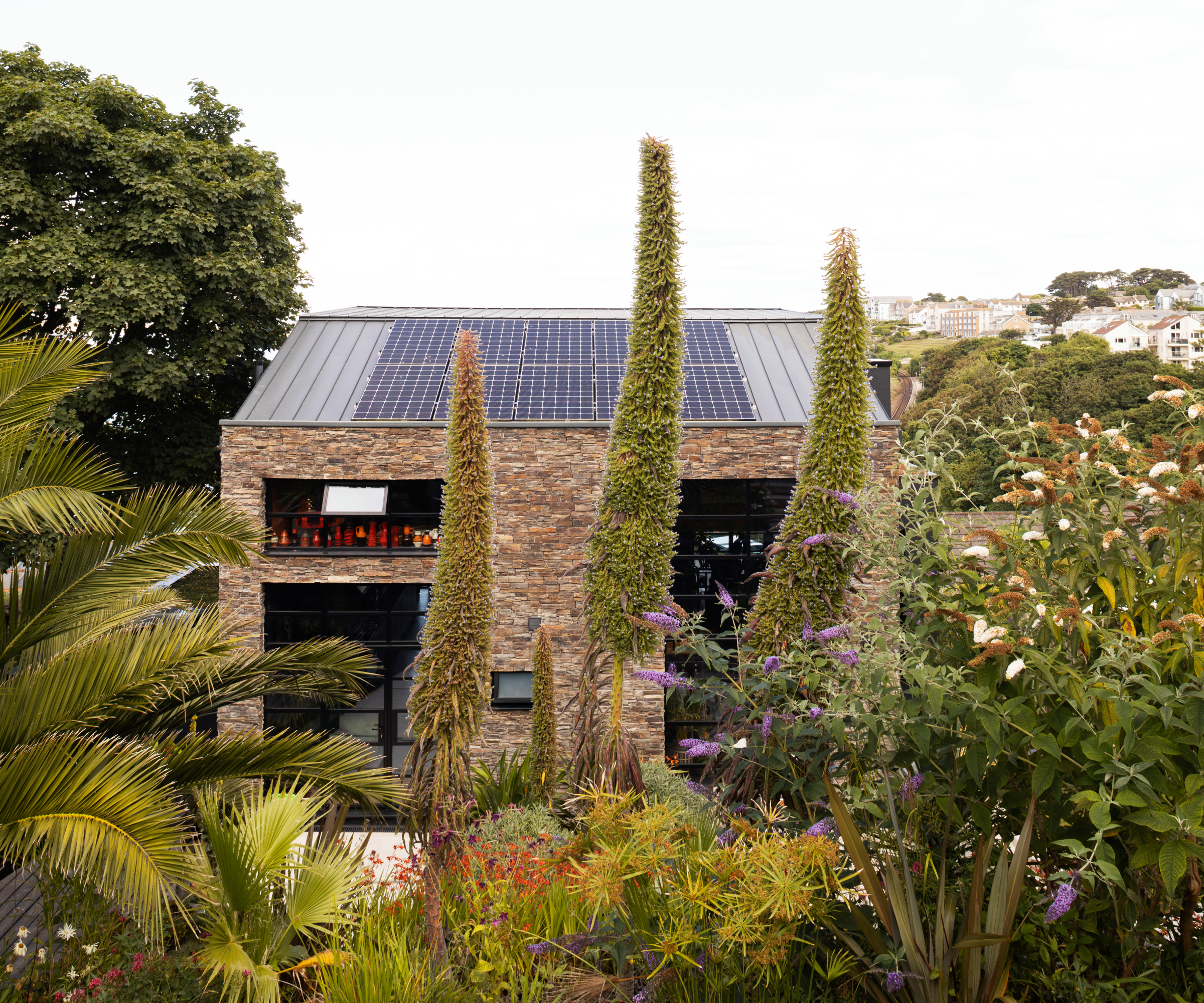 modern brick self build in dense gardens with solar panels on black roof