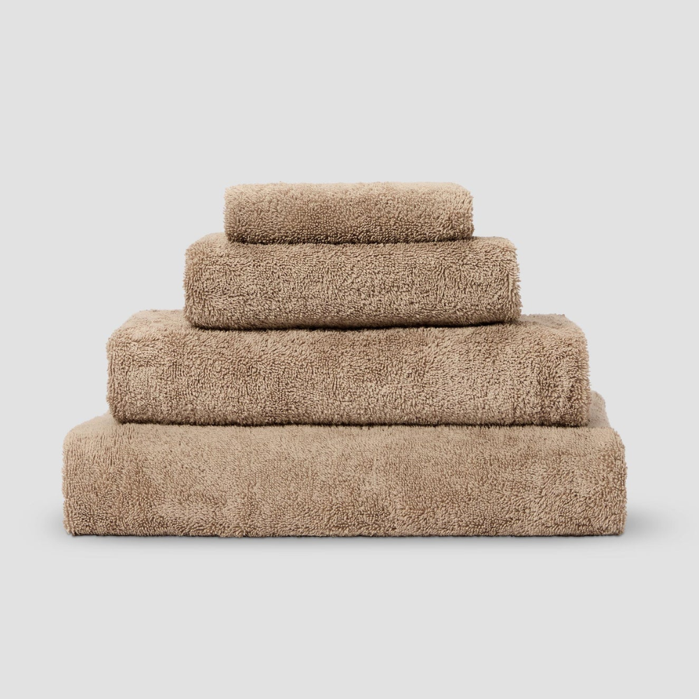 A pile of fluffy towels on a grey background in a taupe shade