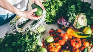 Woman unpacking vegetables and fruits out of sustainable carry bag and onto table