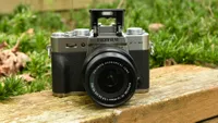 The Fujifilm X-T30, one of the best mirrorless cameras, sitting on a wooden bench against a backdrop of vegetation