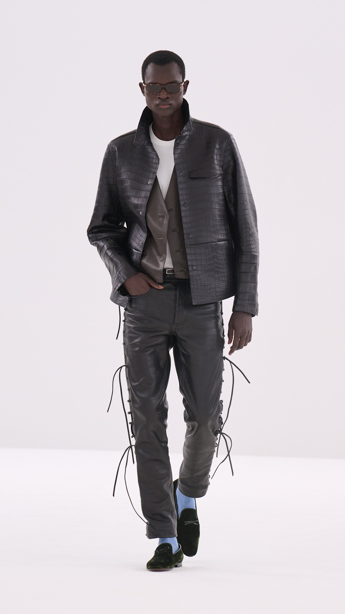 a Tom Ford model wearing a navy croc embossed jacket, leather black pants, and black loafers