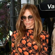 Jennifer Lopez wearing a black-and-orange floral dress and orange Hermès Birkin bag while out in Beverly Hills on Mother's Day May 2024