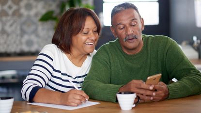 A married couple sit at a table going over expenses.