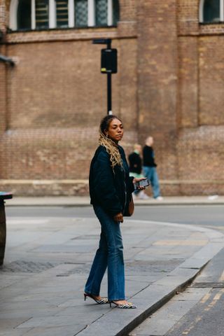 Influencer wears black leather bomber jacket with jeans.