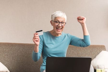 A woman looks excited while checking her credit card statement online. 