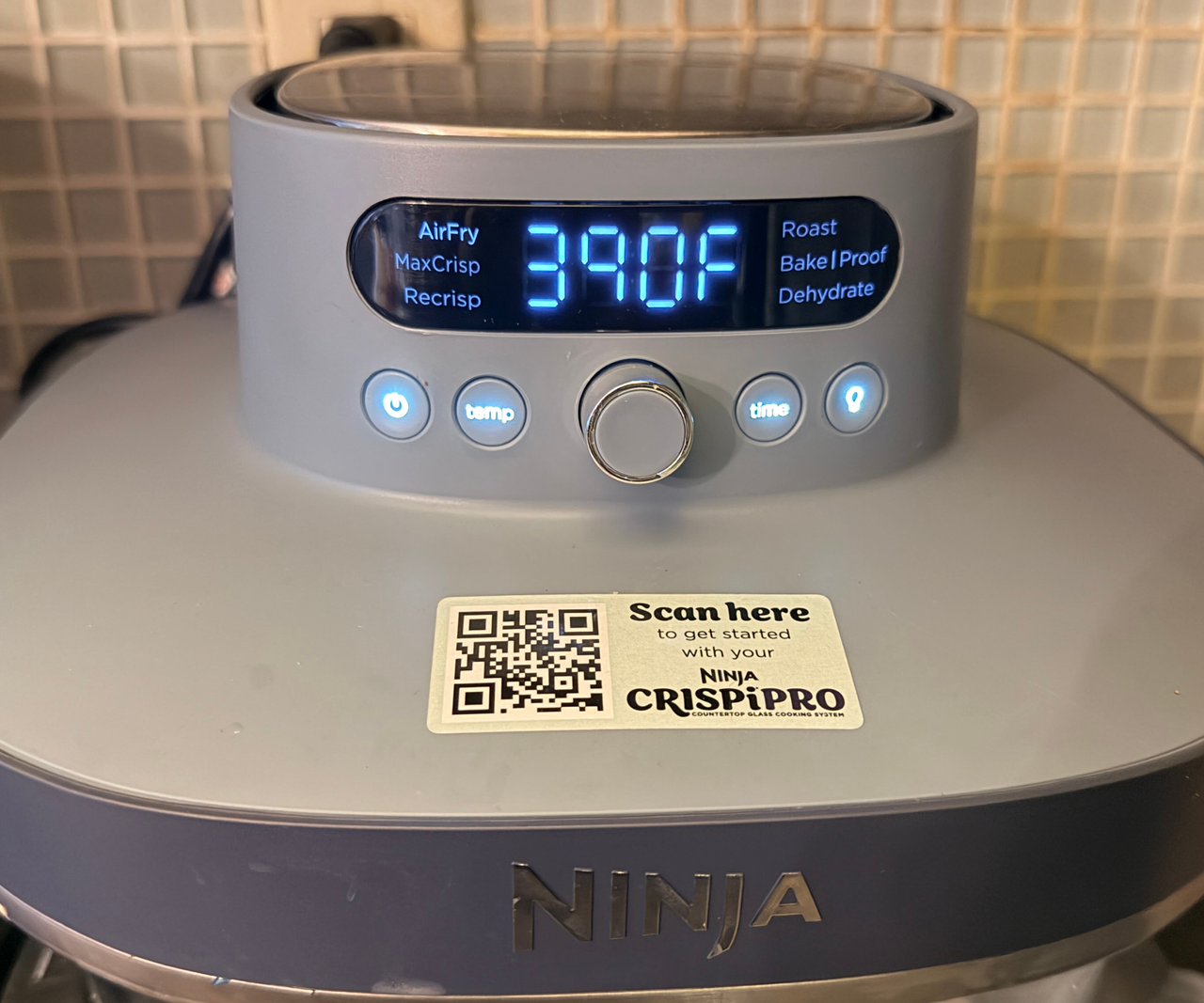 A cluse up of the bright blue LED display on the Ninja Crispi air fryer head.