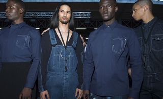 Four male models wearing clothing by Givenchy in dark blue shades.