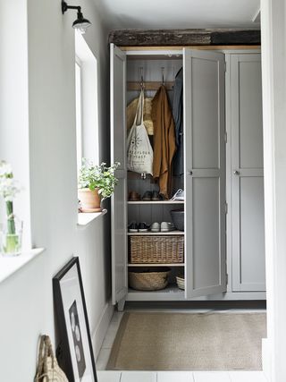 entryway closet with doors open, hanging clothes and drawers inside, rug on the floor