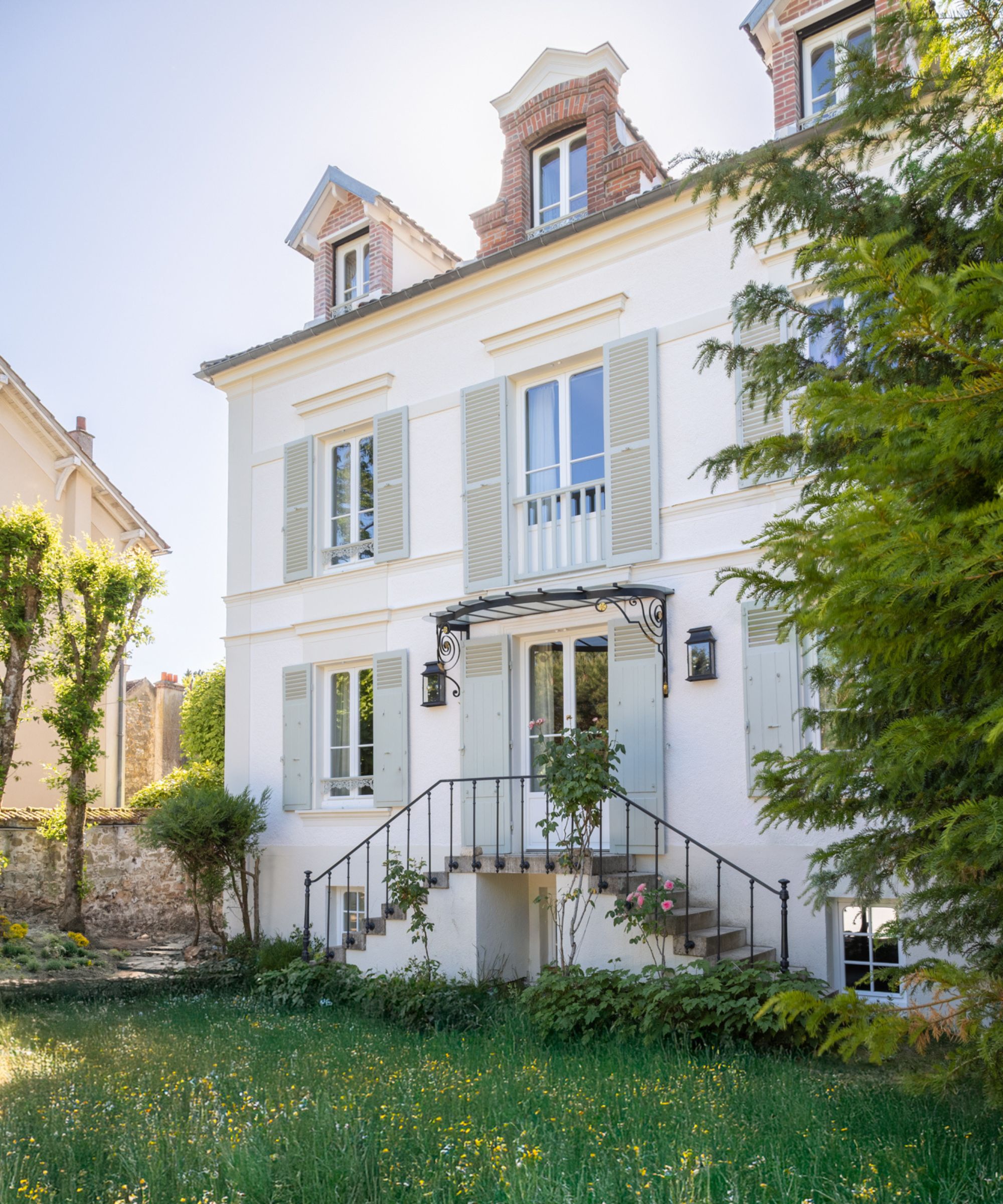 Exterior of a French house with white walls and pale blue shutters