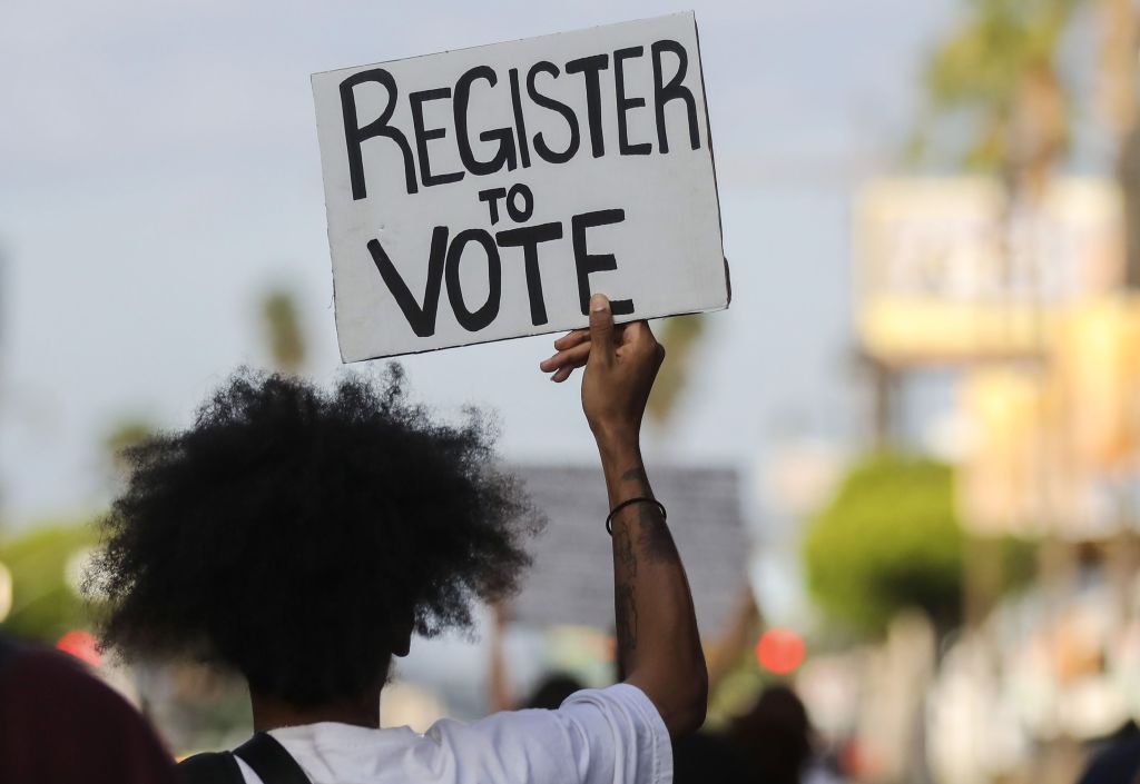 A protester carries a &amp;#039;Register to Vote&amp;#039; sign