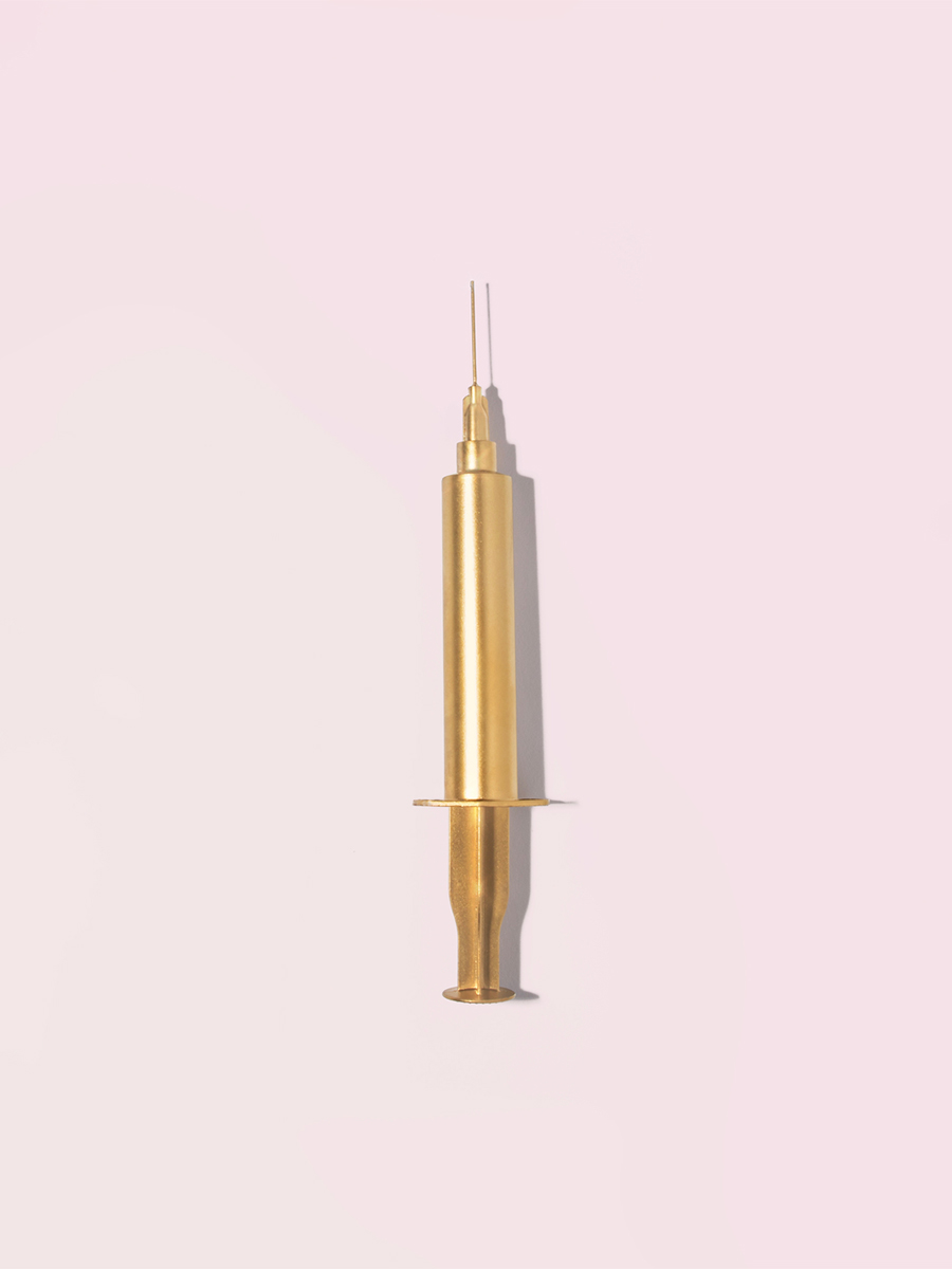 Gold injection needle on a pink background