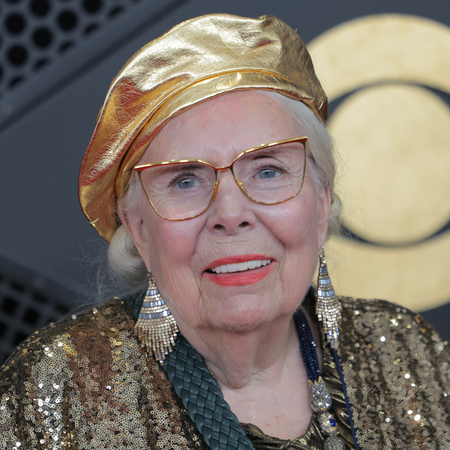 an older white woman with a red lipstick and gold outfit