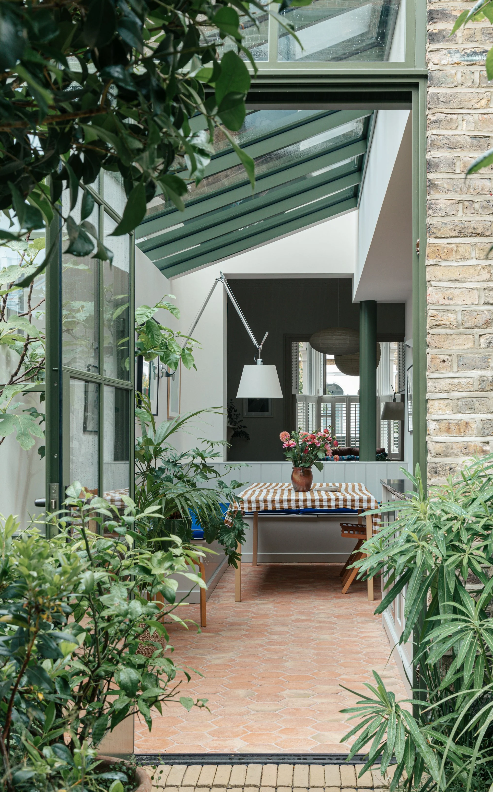 Kitchen extension with green steel-framed glazing and terracotta floors