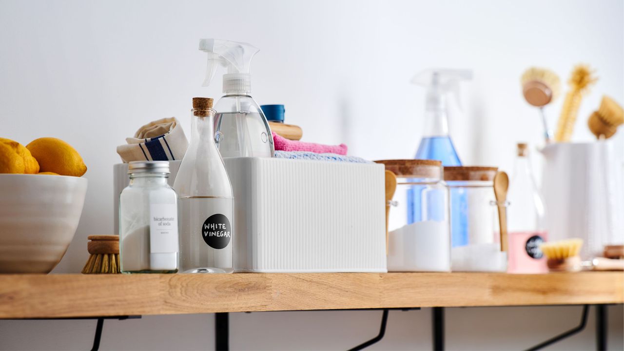 Wooden shelf filled with all kinds of cleaning products, including white vinegar and lemons