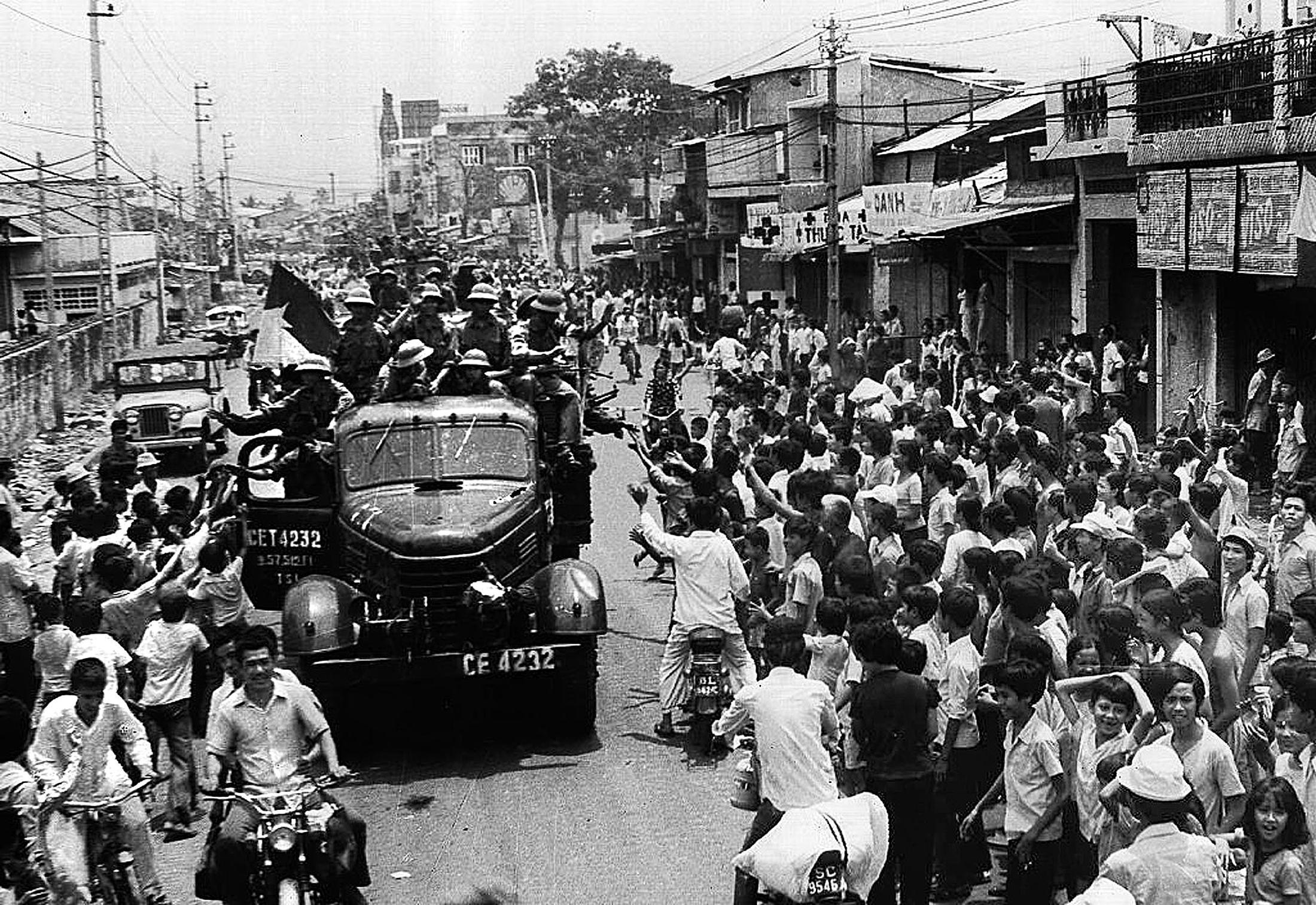 Saigon residents taking to the street to welcome the arrival of communist troops on trucks