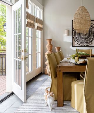 dining room with light beige walls, linen chair covers and rattan pendant light