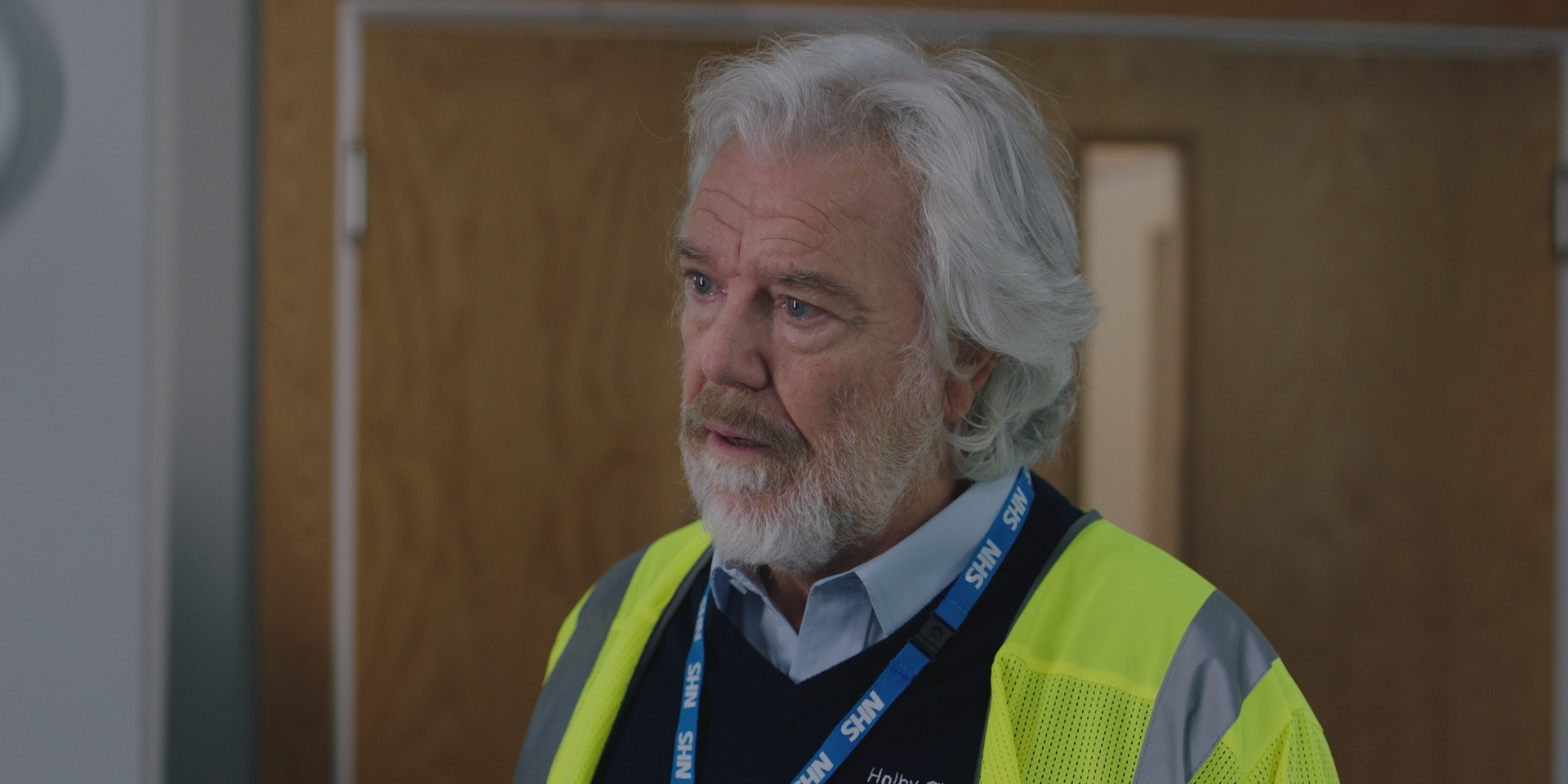 EMBARGOED 26/09 Bill Fellows as Terry, wearing a high vis yellow vest and a hospital lanyard.