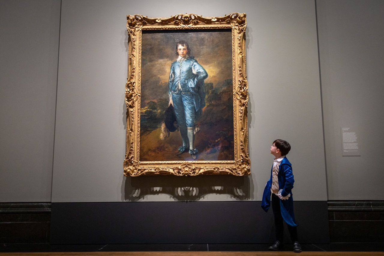 A child poses in front of &quot;The Blue Boy&quot; by English artist Thomas Gainsborough at the National Gallery in London on January 24, 2022, to promote its first display in the UK for one hundred years. Photo by Tolga Akmen / AFP.