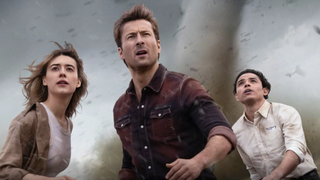 Kate (Daisy Edgar-Jones), Tyler (Glenn Powell) and Javi (Anthony Ramos) brace themselves as a tornado appears in the background in Twisters