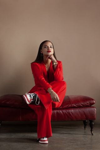 a portrait of denise vasi wearing a red suit