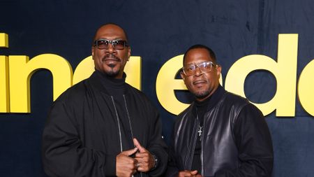 Eddie Murphy and Martin Lawrence both in all black outfits and sunglasses on the red carpet. They are both looking at the cameras.
