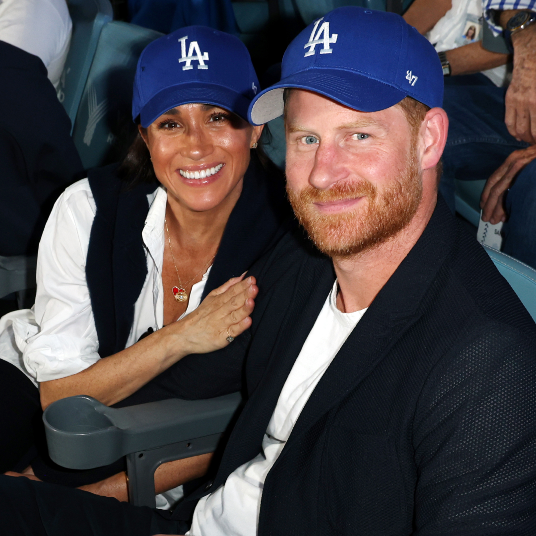 Meghan Markle holding Prince Harry's arm wearing LA Dodgers hats