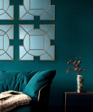 A mirror idea inspired by the Art Deco movement in living room with teal wall paint decor, teal sofa and faux flowers