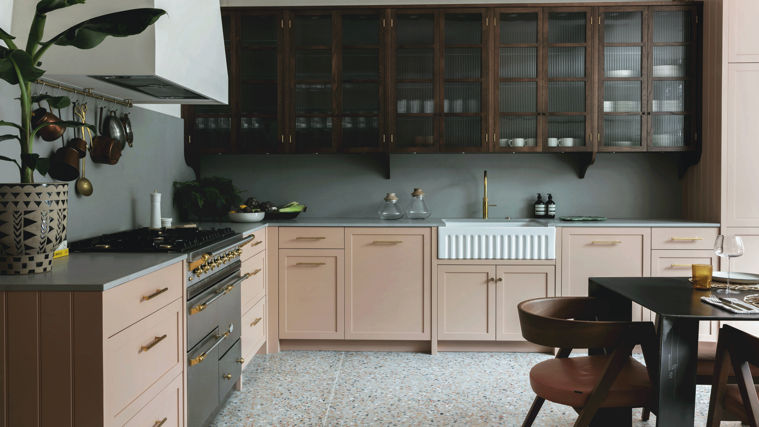 Two-tone kitchen with pink base cabinets and wood wall cabinets with terrazzo floor