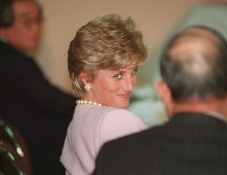 Princess Diana wearing a lavender suit and pearls smiling