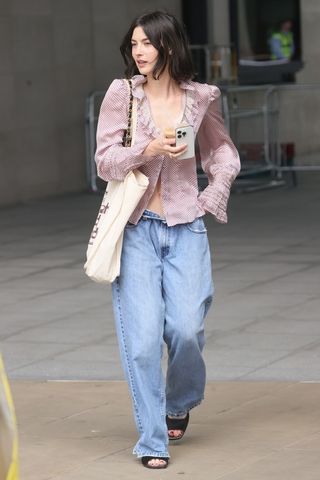 Gracie Abrams wearing a ruffled shirt and baggy jeans
