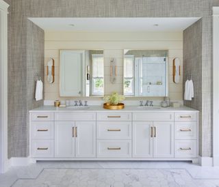 Neutral bathroom design with double white vanity, textured wallpaper and brass hardware