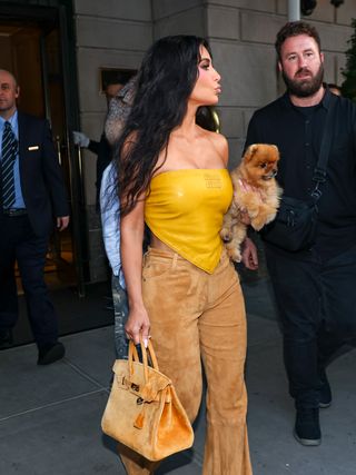 Kim Kardashian is seen leaving The Ritz-Carlton on August 14, 2024 in New York City wearing a mustard miu miu bandana top and an hermes birkin