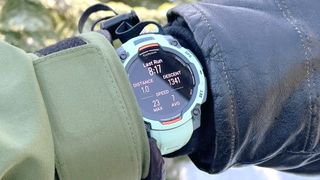 Garmin Instinct 3 on a user's wrist shown up-close in between a ski glove and jacket