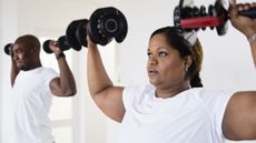 Woman and man exercising with dumbbells at home