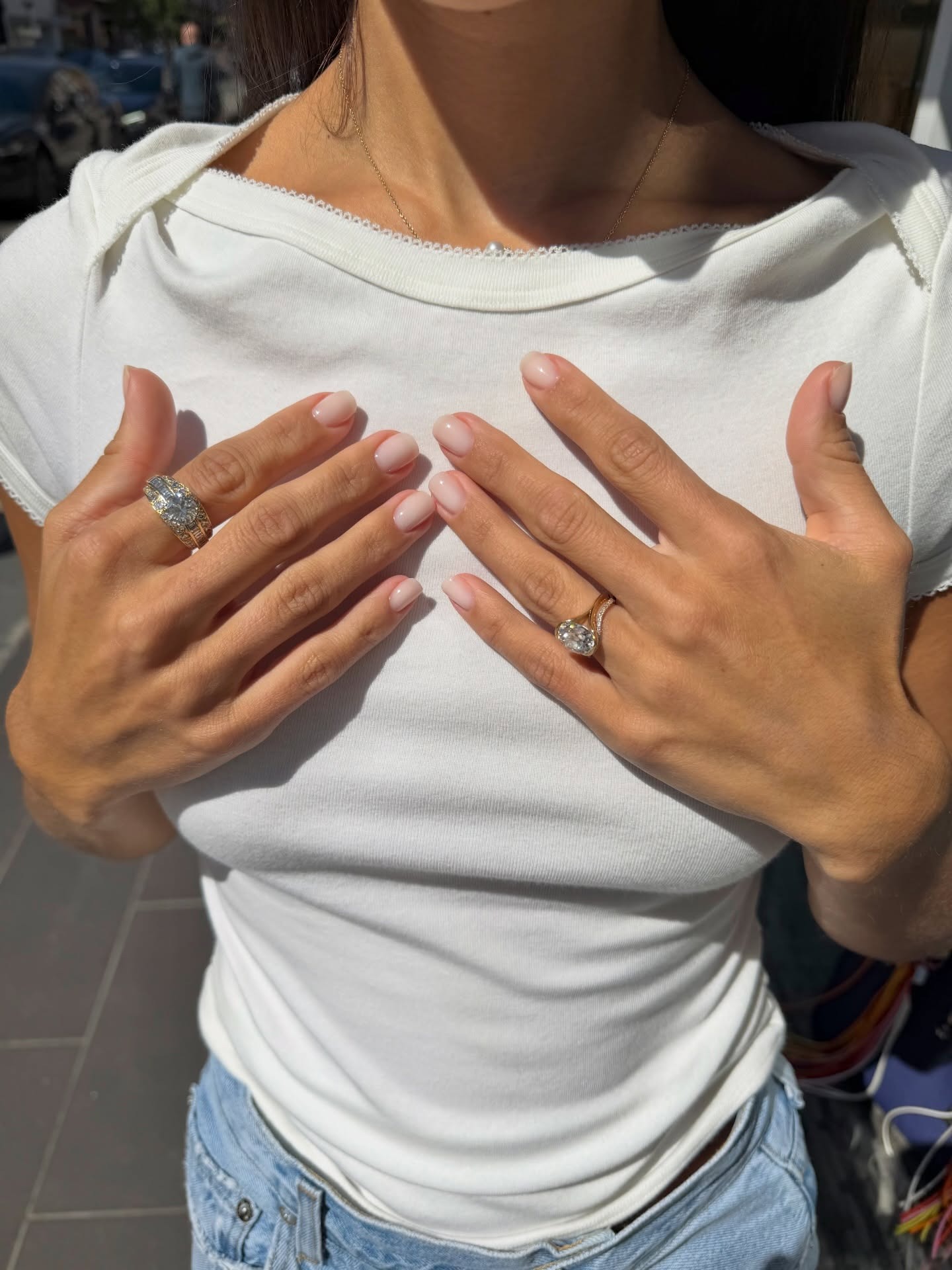 A woman wearing a white T-shirt with a high-shine, milky manicure