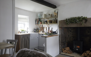 a small open plan kitchen with a fireplace next to it, one of the best cabin decor ideas