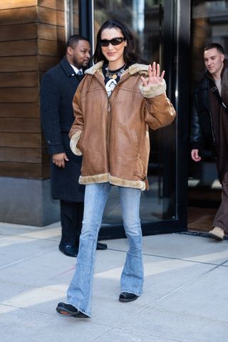 Bella Hadid wears flare jans with brown leather jacket.