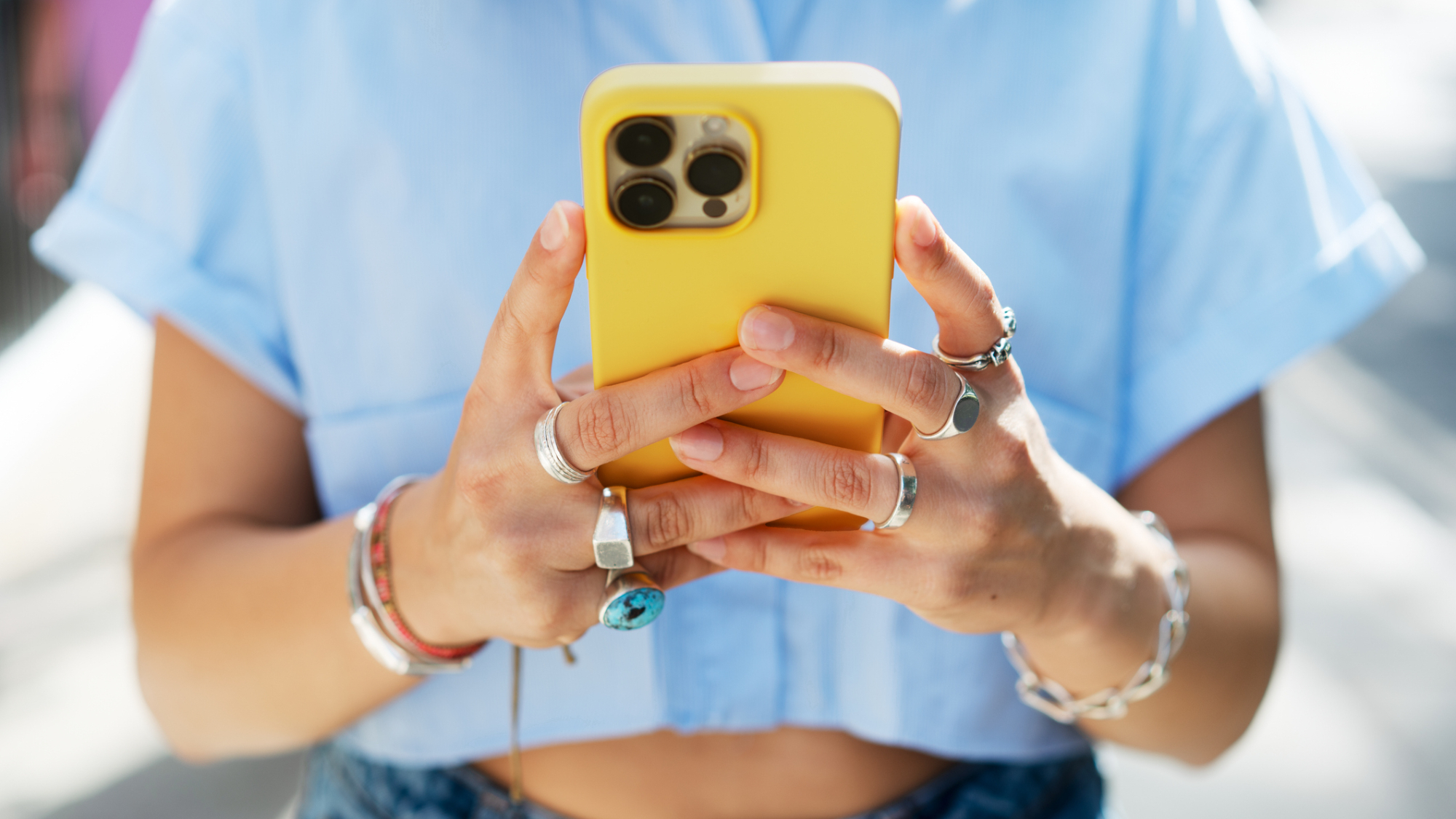 A person holding a yellow iPhone in front of them with both hands.