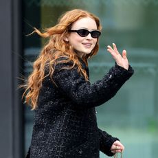 Sadie Sink wearing oval sunglasses waving at the camera