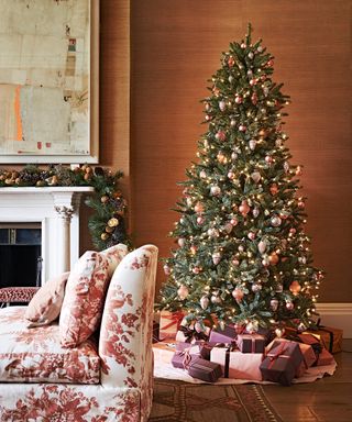 Christmas tree ideas with blush pinkl, silver and gold decorations in a living room with brown wallpaper