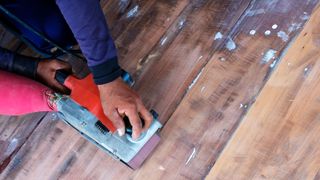 Top down shot of stripped wooden floor being sanded with a belt sander