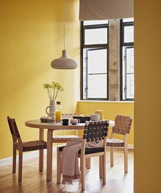 Yellow dining room with wooden dining table and chairs by Crown