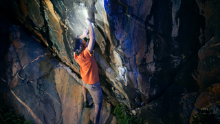 Man bouldering at night with a headlamp on