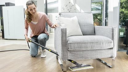 Best steam cleaner: woman cleaning under sofa with Karcher SC3 steam cleaner
